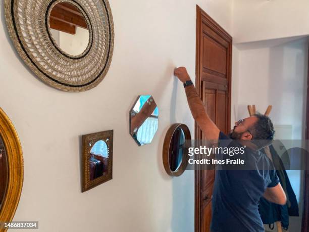 man hanging mirrors in the hall at home - feng shui house stock pictures, royalty-free photos & images