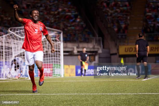 ecstatic male soccer player lifts his arm and pumps celebratory fist in the air - soccer striker stock pictures, royalty-free photos & images