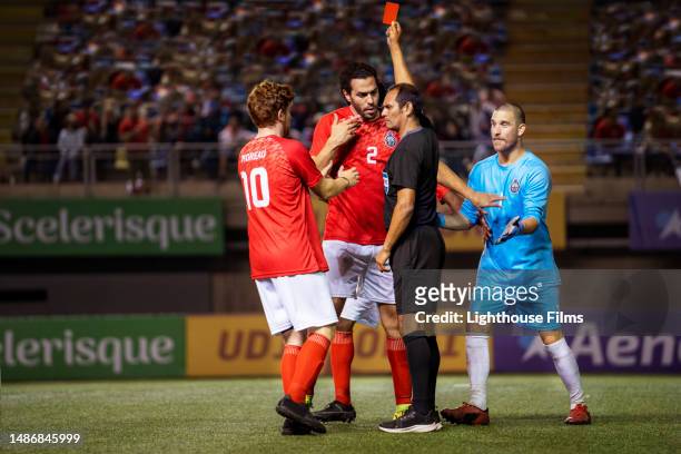 referee sternly gives a soccer player a red card as they try to argue with him - referee card stock pictures, royalty-free photos & images