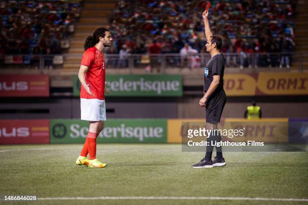 referee gives a red card penalty during a soccer match as the player argues with him - referee card stock pictures, royalty-free photos & images
