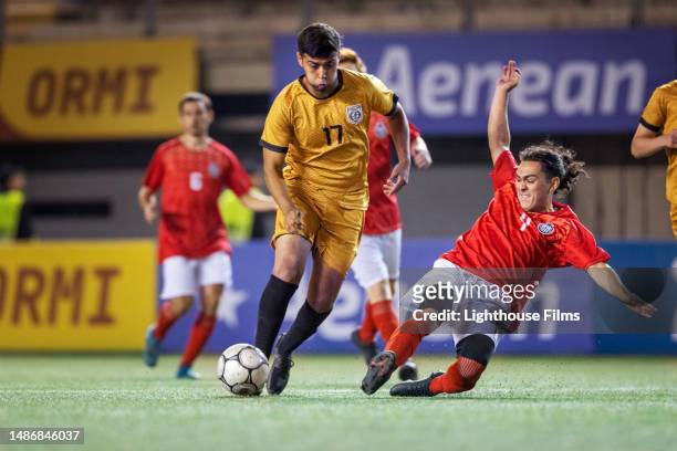 competitive professional soccer player aggressively slide tackles toward opposing player in an attempt to steal ball - spiel - sport stock-fotos und bilder