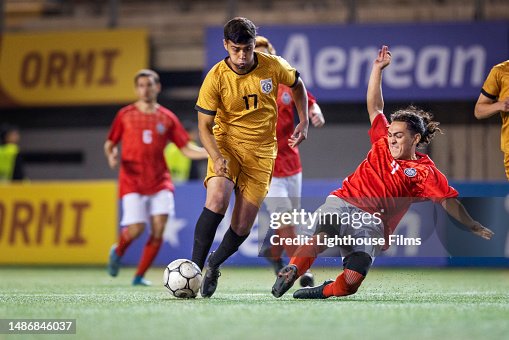 Competitive professional soccer player aggressively slide tackles toward opposing player in an attempt to steal ball Competitive professional soccer player aggressively slide tackles toward opposing player in an attempt to steal ball