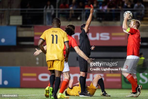 international referee gives red card to a soccer player while they argue and make frustrated gestures - referee card stock pictures, royalty-free photos & images