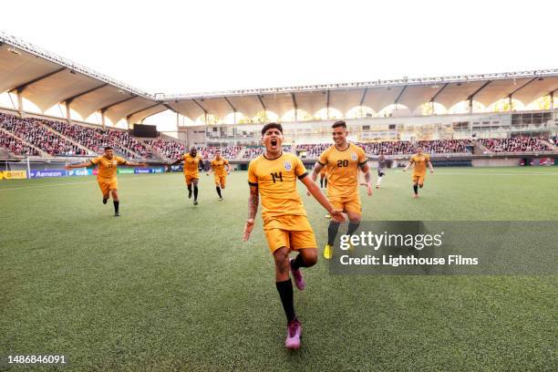 ecstatic male soccer player runs down a stadium field cheering in celebration during an international match - calcio internazionale foto e immagini stock