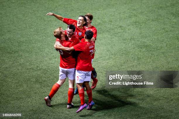 thrilled group of professional male soccer players cheer and jump up and down while celebrating goal - equipo de fútbol fotografías e imágenes de stock