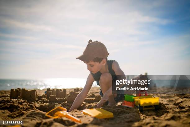 kind spielt in den sommerferien am strand - kind sandburg stock-fotos und bilder