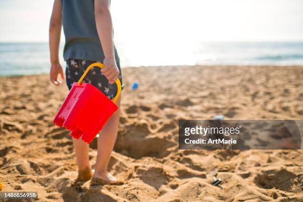 child plays on the beach on summer holidays - bucket and spade stock pictures, royalty-free photos & images