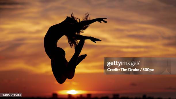 silhouette of woman jumping against sky during sunset - drake one dance stock-fotos und bilder