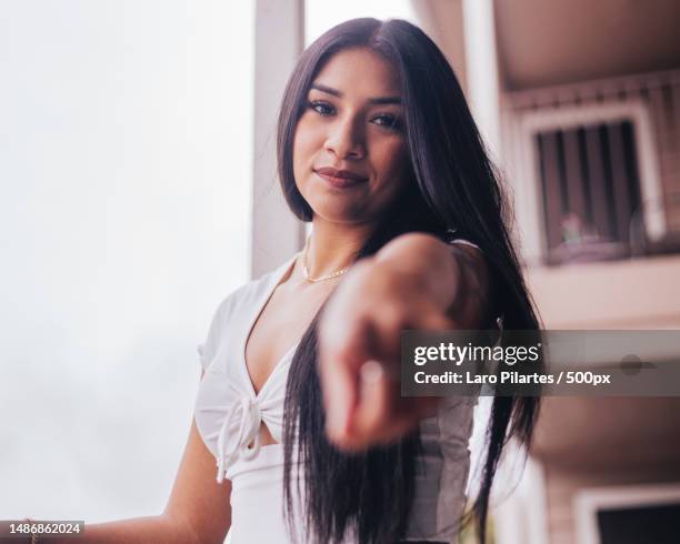 portrait of young woman gesturing towards camera while standing by window,corpus christi,texas,united states,usa - corpus christi stock pictures, royalty-free photos & images