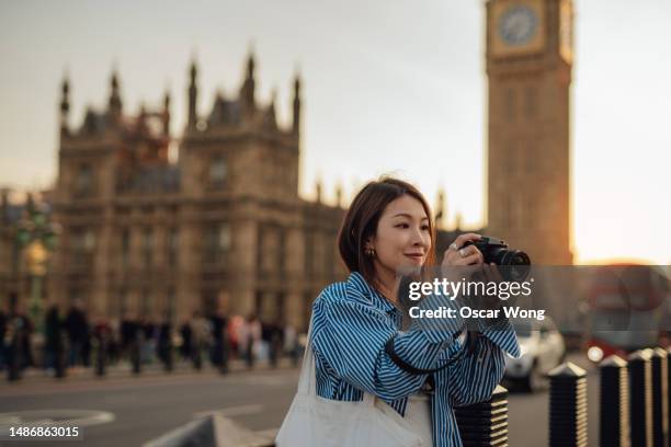 female asian tourist taking photos with camera while exploring the city of london - luxury women stock pictures, royalty-free photos & images