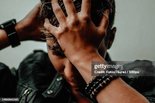 close-up of young woman with hands in hair wearing leather jacket and beaded bracelet - hands on head stock pictures, royalty-free photos & images