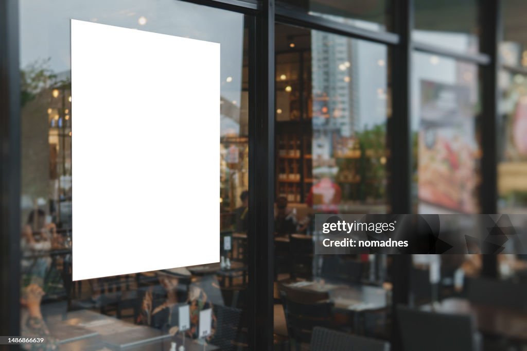 Blank poster on window glass template. Empty placard attached on window glass. Billboard and various business promotions for retail stores and restaurants.