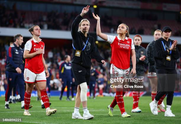 Leah Williamson of Arsenal, wearing a knee support for their ACL injury, acknowledges the fans as they walk with players of Arsenal after their...