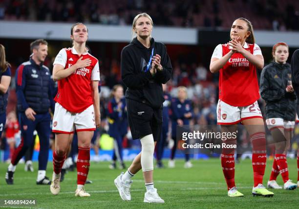 Leah Williamson of Arsenal, wearing a knee support for their ACL injury, acknowledges the fans as they walk with players of Arsenal after their...