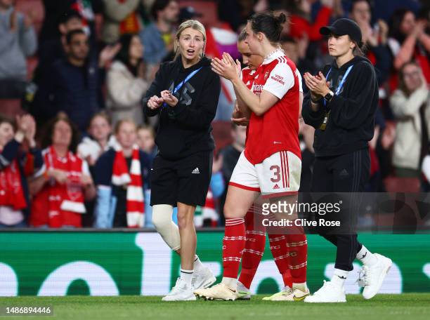 Leah Williamson of Arsenal, wearing a knee support for their ACL injury, speaks with Lotte Wubben-Moy as they applaud the fans after their side's...