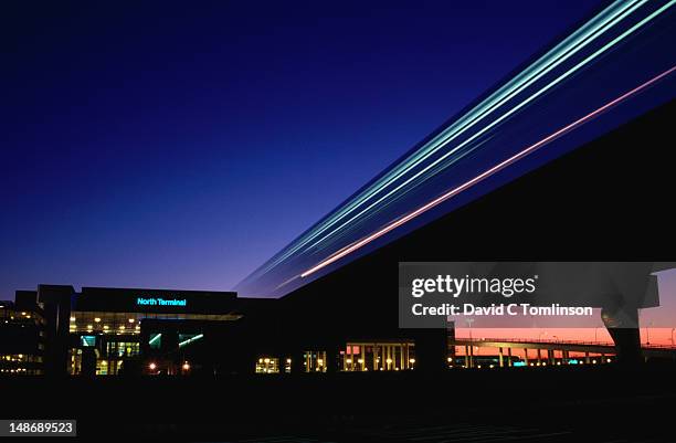 the north terminal of gatwick airport, one of london's major airports, at night showing the movement of the monorail. - gatwick airport stock pictures, royalty-free photos & images