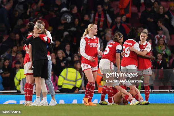 Lotte Wubben-Moy of Arsenal is embraced by Vivianne Miedema and Leah Williamson, wearing a knee support for their ACL injury, as players of react...