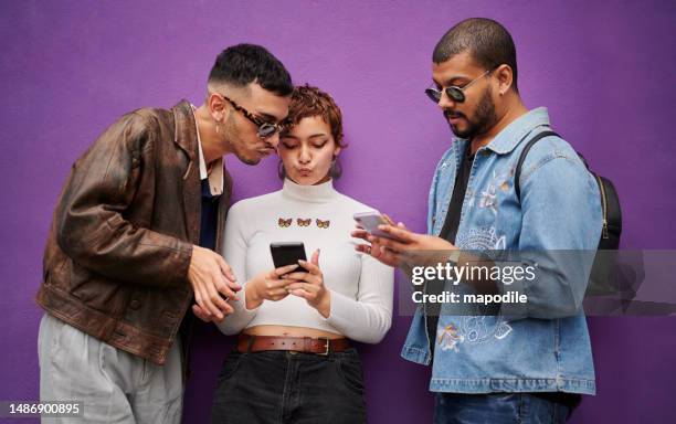 diverse friends checking their phones together against a purple wall - fashion young man stockfoto's en -beelden