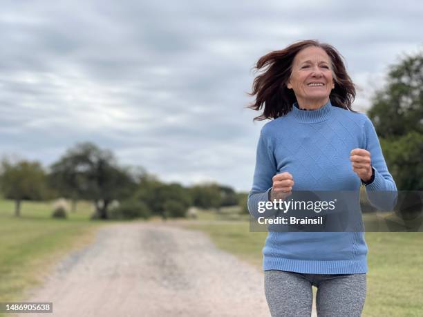 senior woman running outdoors - senior women jogging stock pictures, royalty-free photos & images