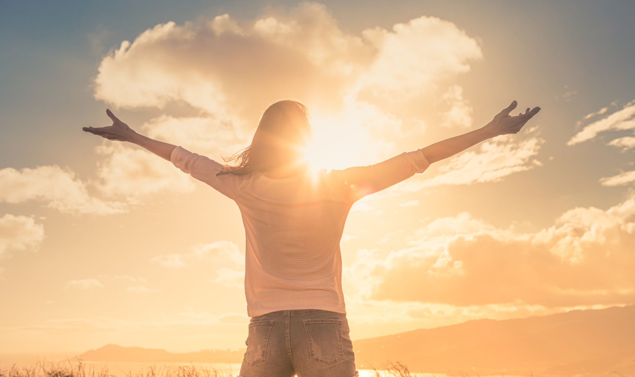 Young woman with hands up the morning sun light finding happiness, peace and hope in nature Young woman with hands up the morning sun light finding happiness, peace and hope in nature