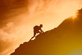 Man climbing up mountain cliff. Working hard to reach goals