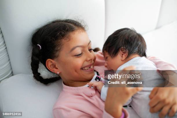 african-american sister hugs her younger brother in the bed - siblings baby stock pictures, royalty-free photos & images