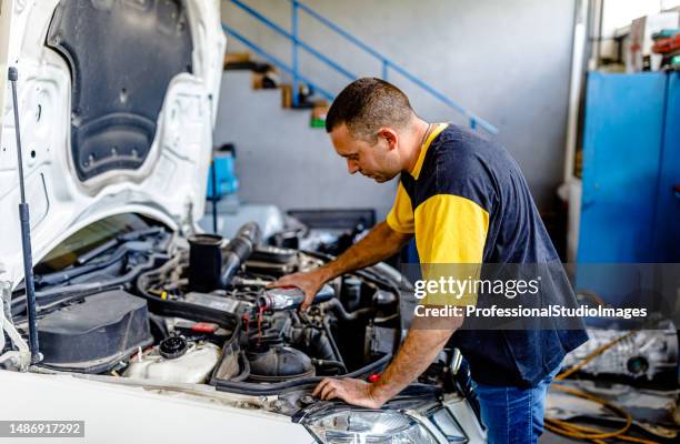 a car mechanic is pouring a coolant into a storage tank in the car. - mutterbricka bildbanksfoton och bilder