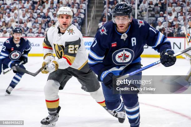 Alec Martinez of the Vegas Golden Knights and Adam Lowry of the Winnipeg Jets follow the play towards the boards during third period action in Game...