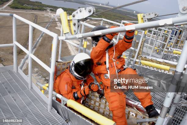 On Launch Pad 39A at NASA's Kennedy Space Center in Florida, two members of space shuttle Endeavour's STS-130 crew, dressed in their helmets and...