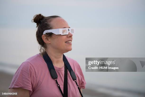 Woman views the partial solar eclipse as the sun rises, Thursday, June 10 at Lewes Beach in Delaware. The annular or â€œring of fireâ€ solar eclipse...