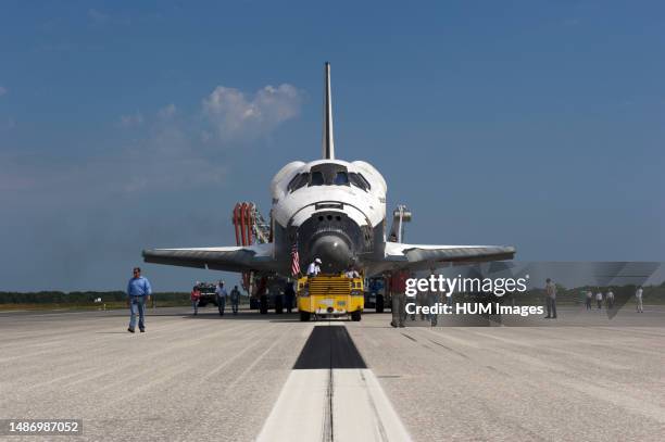 Workers accompany space shuttle Atlantis as it makes its slow trek from the Shuttle Landing Facility to Orbiter Processing Facility-2 for the last...
