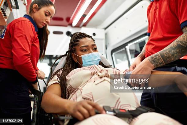 pregnant black woman being cared for inside ambulance - paramedic uniform stock pictures, royalty-free photos & images