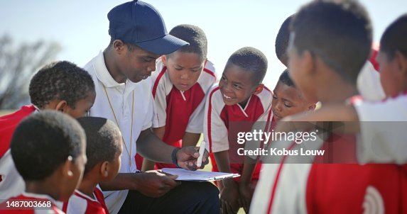 Kids, soccer and man coaching team with outdoor training sketch, games strategy and competition planning. Listening, leadership and african person drawing goals with football player, children or boys Kids, soccer and man coaching team with outdoor training sketch, games strategy and competition planning. Listening, leadership and african person drawing goals with football player, children or boys