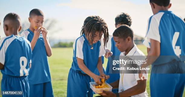 snack break, soccer and children with a coach at sports practice, game or match. fruit diet, eating and young football players with food for nutrition during a competition or training with a man - nutrition coach stock pictures, royalty-free photos & images