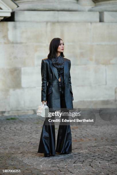 Heart Evangelista wears a black with white polka dots print pattern silk scarf, a black shiny leather studded shoulder-pads / belted long blazer...