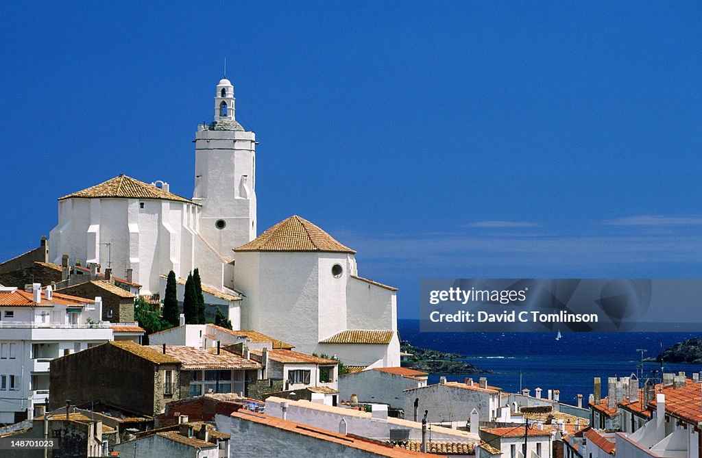 Village church on hillside with Mediterranean in background.