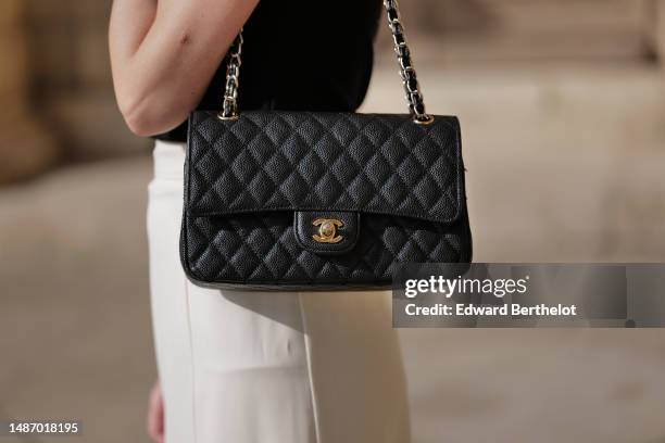 Alba Garavito Torre wears a black high neck / short sleeves t-shirt, a black shiny grained leather Timeless shoulder bag from Chanel, a white high...