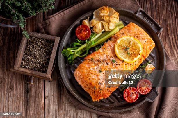 gebratener lachs in der eisenpfanne - lachs stock-fotos und bilder