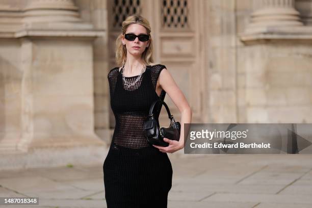 Natalia Verza wears black large small sunglasses from Miu Miu, diamonds earrings, silver large chains necklaces, a black fishnet / mesh long tank-top...