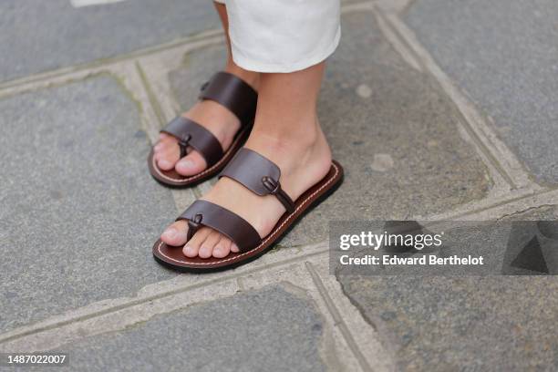 Diane Batoukina wears white denim pants, black shiny leather large asymmetric straps sandals, during a street style fashion photo session, on April...