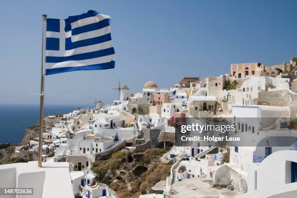 greek flag and cliffside houses. - griekenland stockfoto's en -beelden