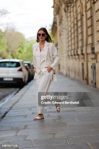 Diane Batoukina wears dark brown large squared sunglasses from Dior, a white buttoned / sleeveless gilet from Boguessa, a white blazer jacket from...