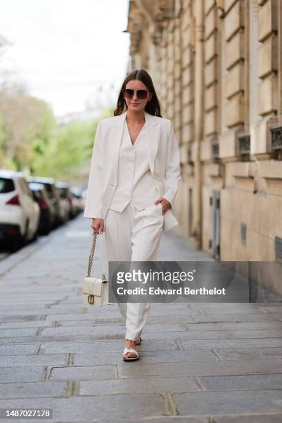Diane Batoukina wears dark brown large squared sunglasses from Dior, a white buttoned / sleeveless gilet from Boguessa, a white blazer jacket from...