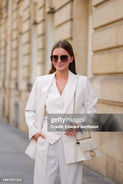 Diane Batoukina wears dark brown large squared sunglasses from Dior, a white buttoned / sleeveless gilet from Boguessa, a white blazer jacket from...