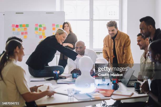 mature female teacher explaining multiracial students over social robot in innovation lab - nieuwe wegen betreden stockfoto's en -beelden