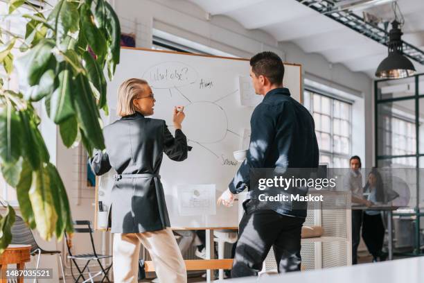 male and female business people planning strategy over white board at office - protocolo fotografías e imágenes de stock