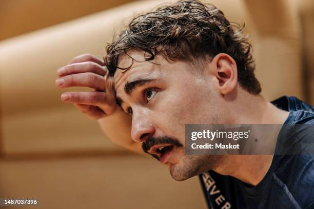 tired male athlete wiping sweat while contemplating at sports court - persistence stock pictures, royalty-free photos & images