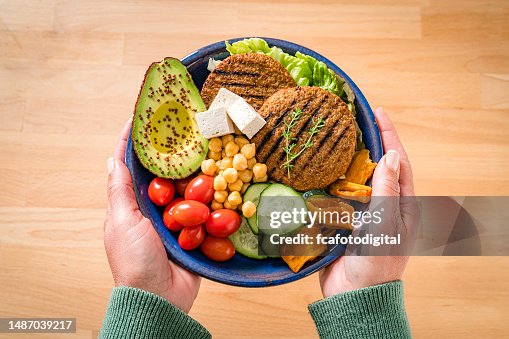 Woman holds a plate with healty plant-based food Woman holds a plate with healty plant-based food