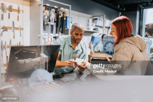 male retail clerk showing bill to female customer at checkout in electronics store - returning goods stock pictures, royalty-free photos & images