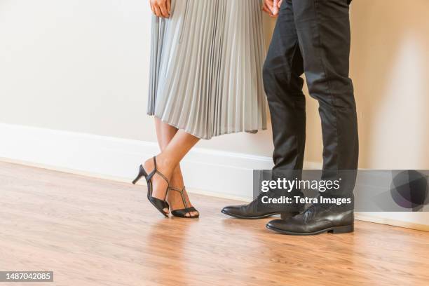 low section of couple standing on wooden floor in apartment - eleganter schuh stock-fotos und bilder